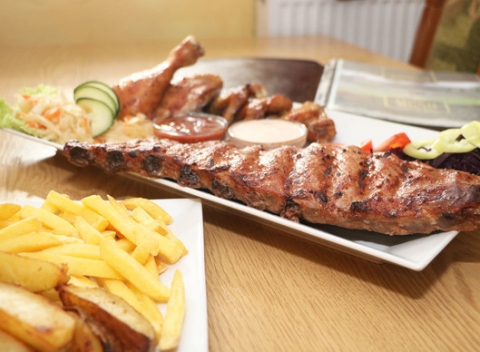 Kilové pečené bravčové rebrá s chlebom, kuracími krídelkami, hranolkami a pečenými zemiakmi.